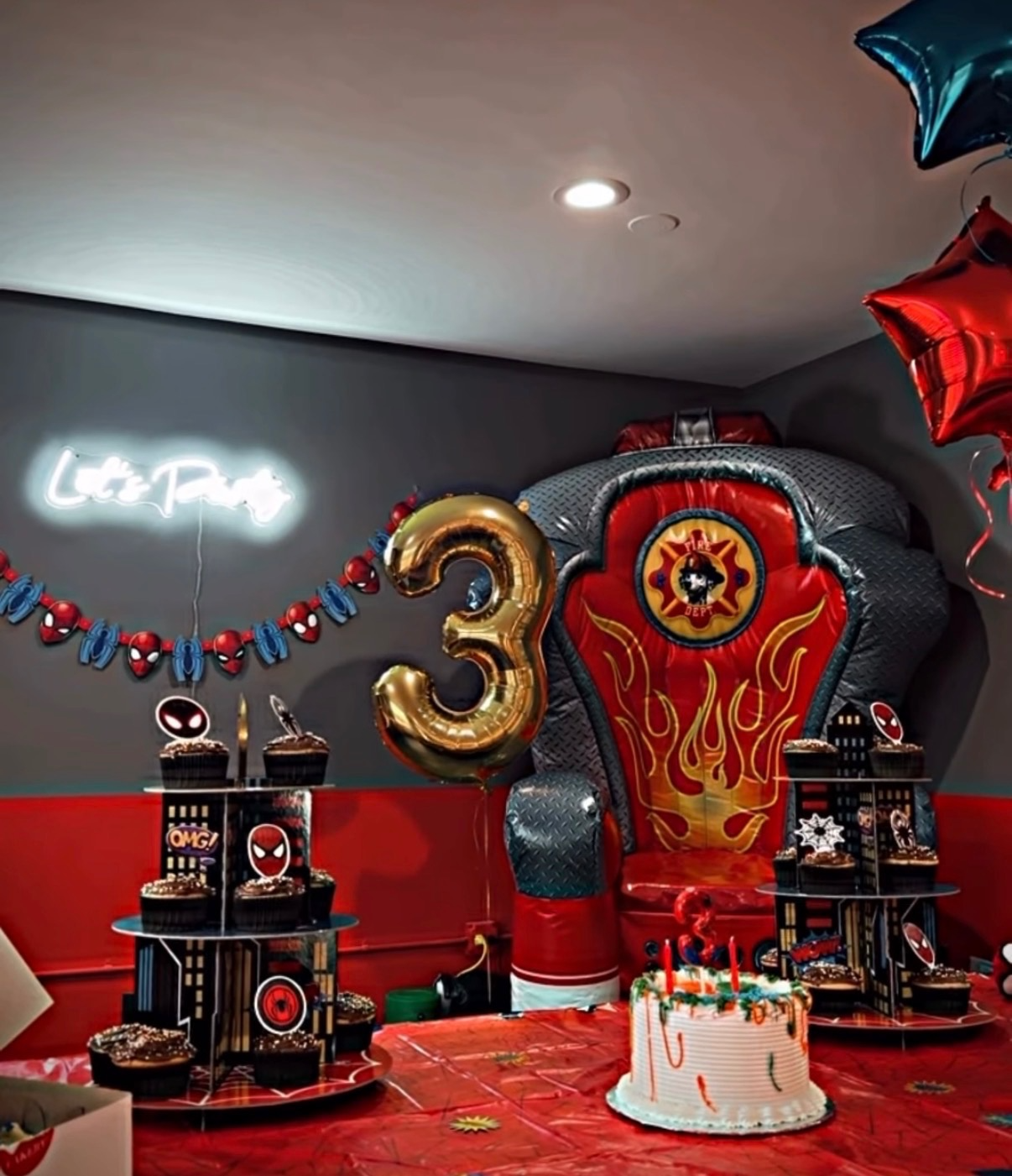 Birthday party setup with cake, balloons, and firefighter throne